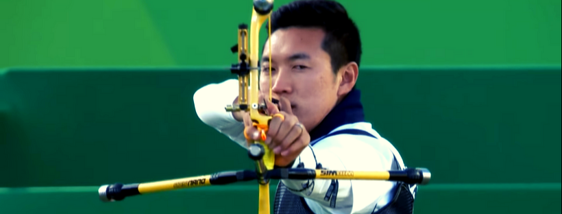 a Korean archer aiming a yellow-black bow and arrow to the camera
